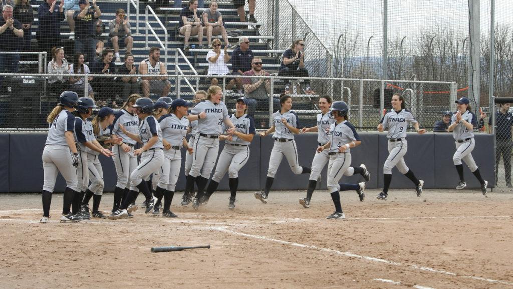 Ithaca College softball team celebrates as senior Alex Wright and sophomore Gabby Laccona run into home plate after sophomore Hailey White hit a grand slam in a 7-0 win against Clarkson University on April 7, 2019. 