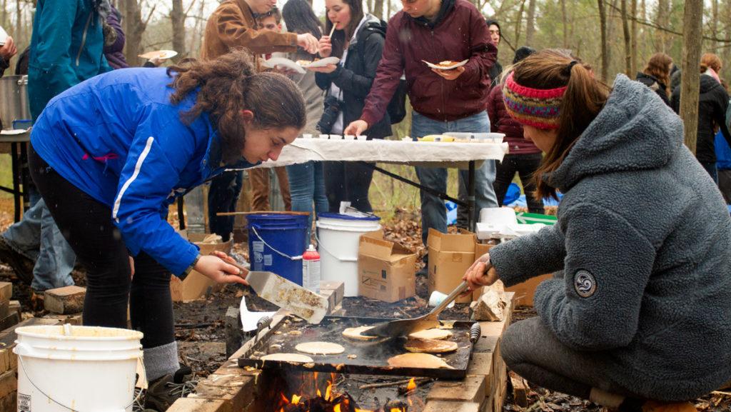 Ithaca College students cook pancakes over a fire at the Sugar Bush Open House on April 27. Sugar Bush is a maple production business run by students taking a natural resources class in the Department of Environmental Studies and Science.