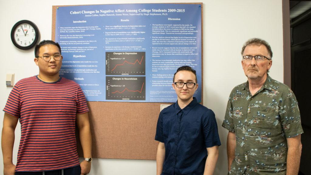 From left, senior Michael Yeung, senior Alex gray and Associate Psychology Professor Hugh Stephenson stand in front of their research. 