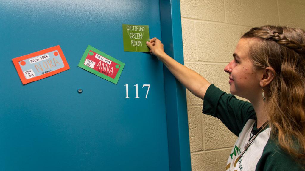 Sophomore Eco-Rep Emily Gronquist places a magnet on a dorm to be Green Room Certified. Students with sustainable living habits can apply for their rooms to be Green Room Certified. 