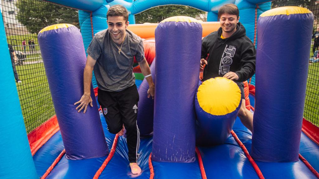 From left, seniors Colin Hay and Harry Margalotti race through an inflatable obstacle course at the Senior Class Picnic on Friday, Sept. 13 on the Campus Center Quads. 