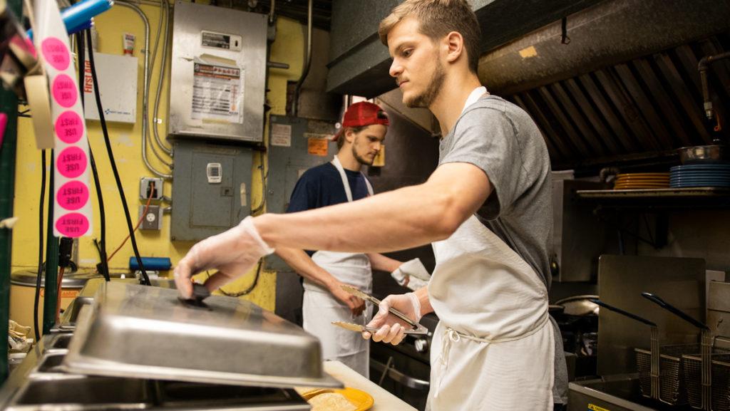 From left, twins Kevin and Corey Adelman prepare food in the kitchen of their restaurant, Bickering Twins. The restaurant has been open since 2017. 