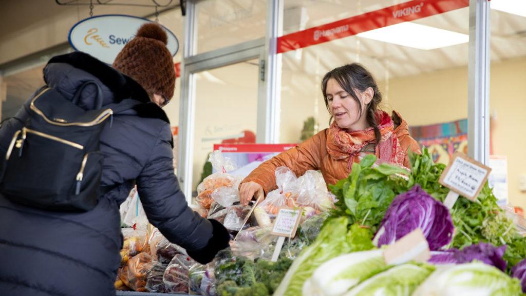 Lucy Garrison-Clauson, co-owner of Stick and Stone Farm, assists a customer at the winter farmers market’s new location in Triphammer Marketplace Jan. 18.