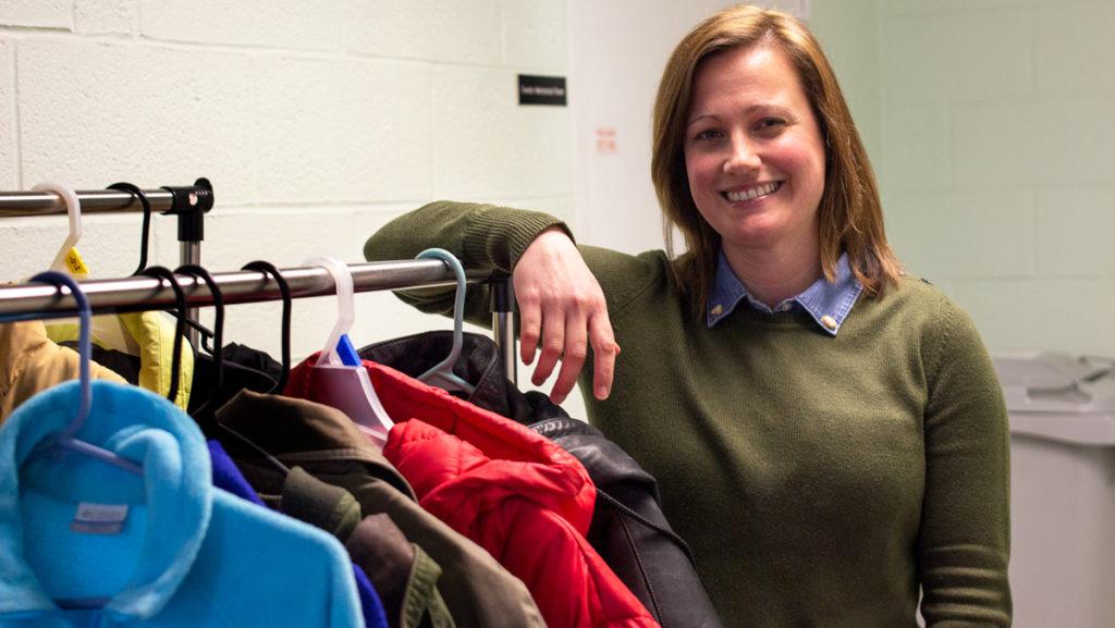 Lis Tomlin, a licensed professional counselor and mental health counselor for CAPS, stands by the coat rack of coats available at the coat drive. 