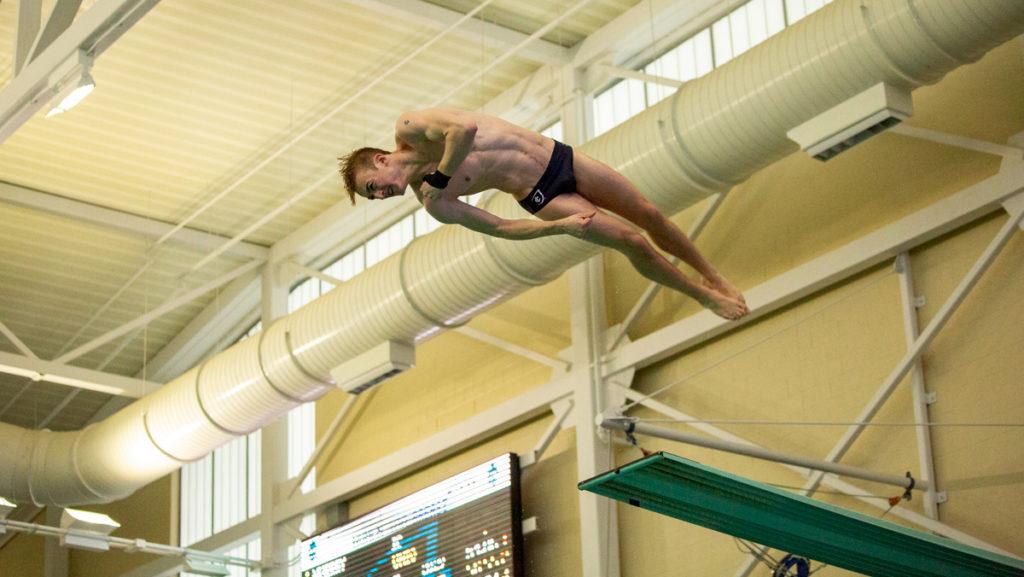 Freshman Ethan Godfrey performs a dive on the 3-meter board during the swimming and diving meet against Union College Jan. 26 at the Kelsey Partridge Bird Natatorium.