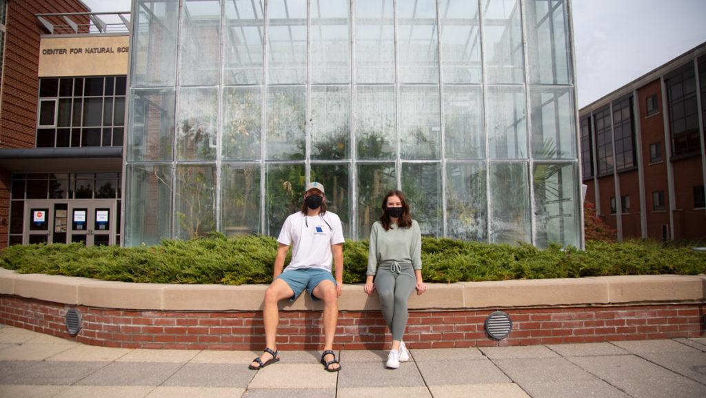 From left, seniors Seth Ormsby and Nina Ng sit in front of the greenhouse. Due to remote learning this semester, students in the aquaponics research group led by Paula Turkon, assistant professor in the Department of Environmental Studies and Science, will not have access to hands-on learning in the greenhouse.