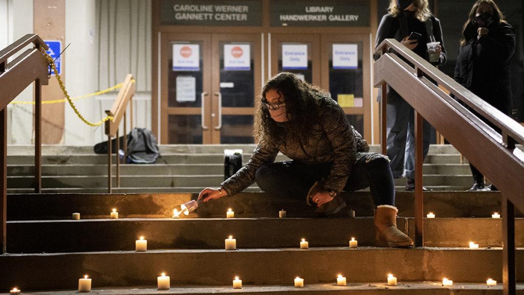 Senior Shoshanna Maniscalco lights candles at a Feb. 24 vigil by the library in honor of faculty members who will be terminated.