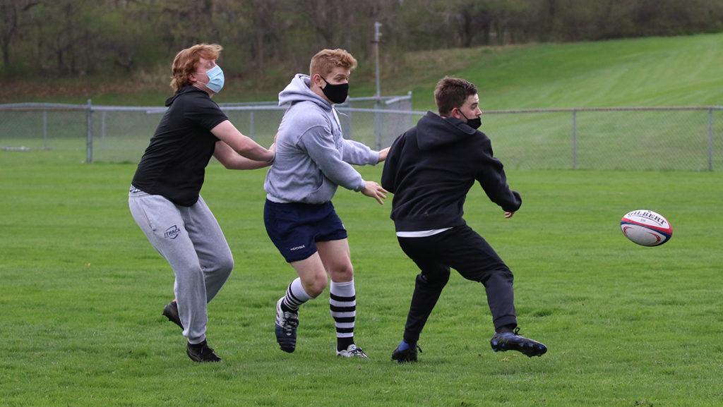 From left to right, senior Will Blum, sophomore Jay Tagliani and sophomore Samuel Plvan take part in a two-hand touch scrimmage during a practice.