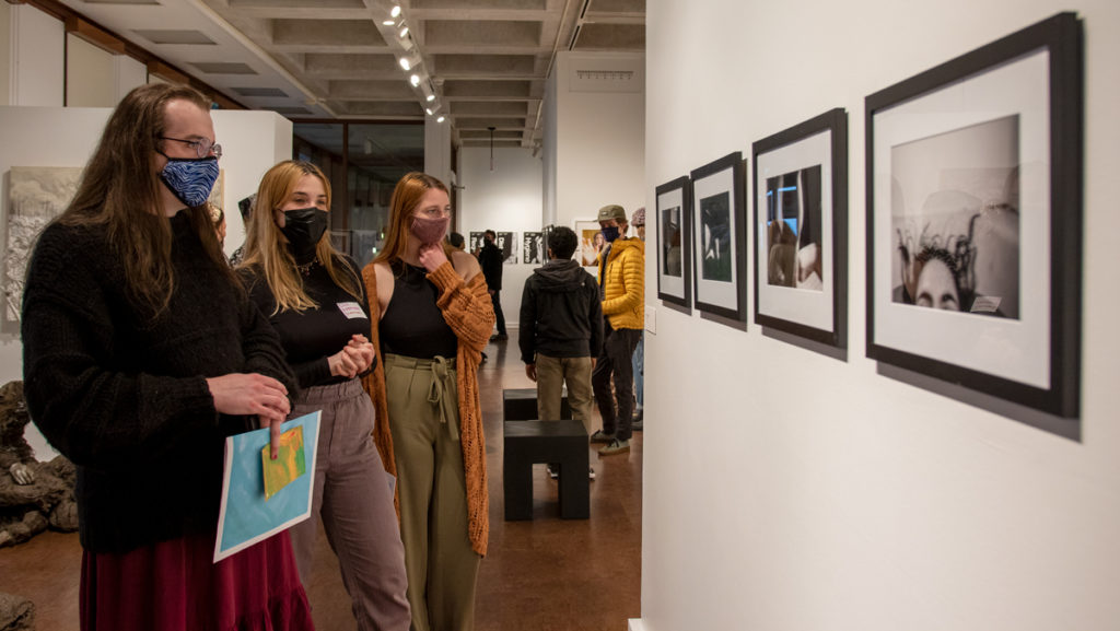 From left, seniors Tom Peyton and Lily Hoffman, along with junior Mary Crawford, view the photographic work by junior Freesia Capy-Goldfarb in the Handwerker Gallery on April 22.