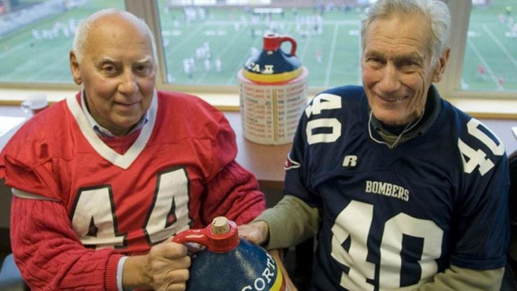From left, former SUNY Cortland football captain Tom Decker and former Ithaca College football captain Richard Carmean 60, co-founders of the Cortaca Jug tradition, hold the original jug. Carmean passed away May 23 at the age of 89.