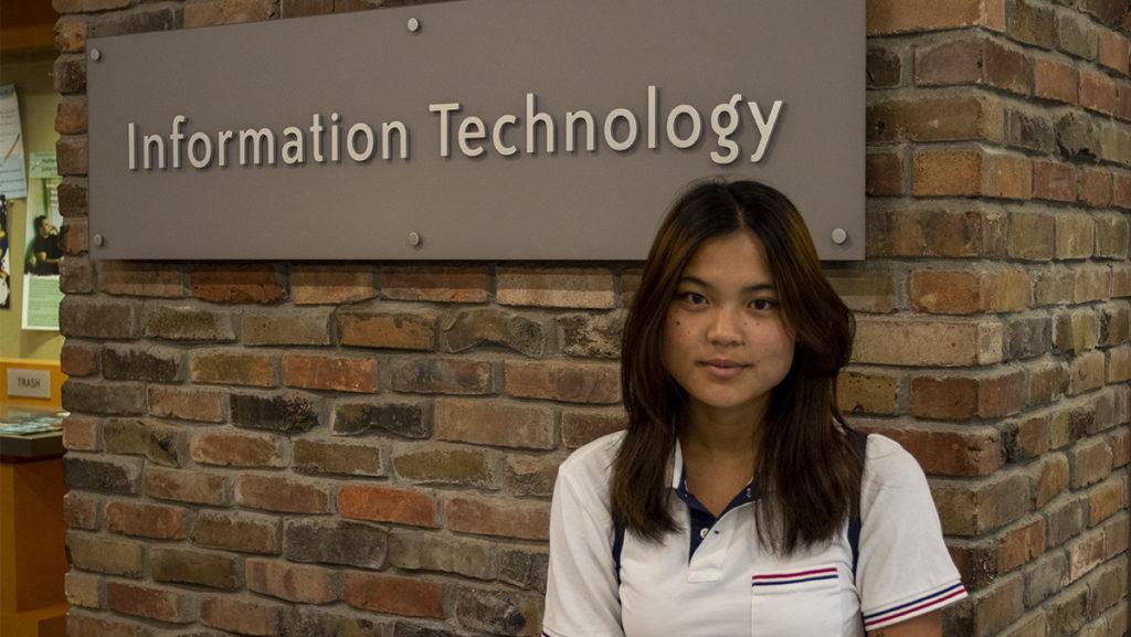Ithaca College senior Mia Loretto posing outside of the Information Technology front desk located in Job Hall. Loretto describes Ithaca College Information Technology as a place of warm, friendly employees