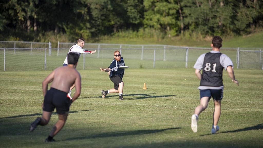 Junior Noah Kamens throws by a defender to his teammate during practice for Nawshus Ultimate. In May, the team advanced to the USA Ultimate Nationals.