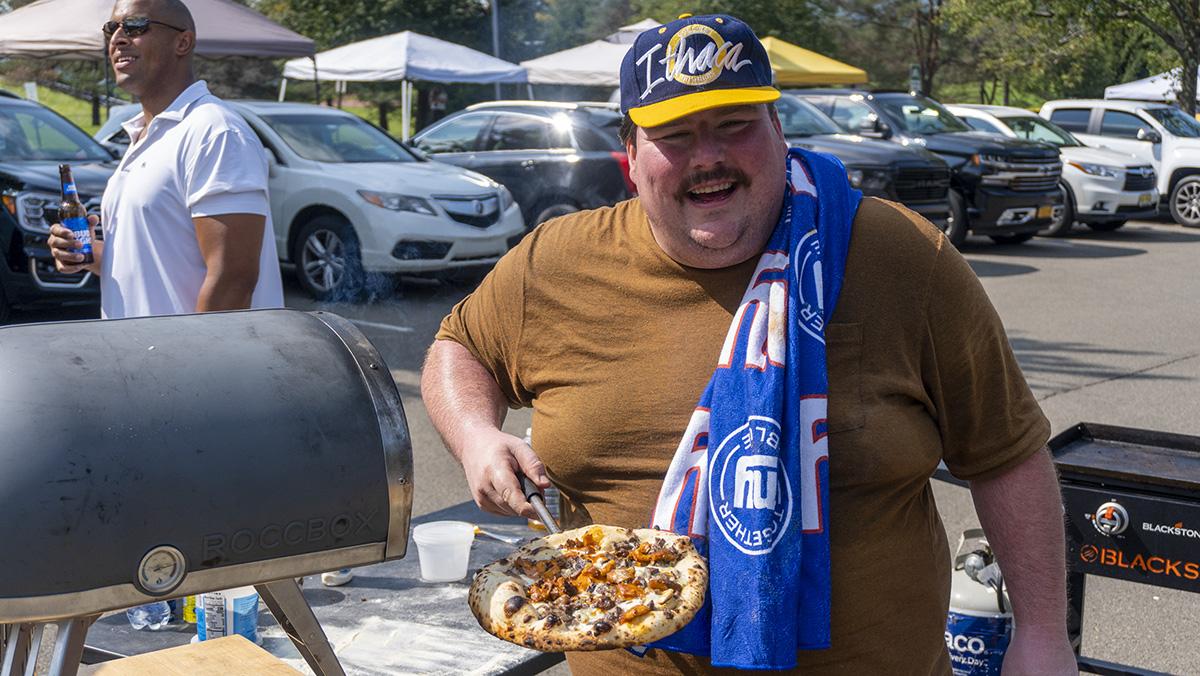 Ithaca College alumni Joe Goetz '07 makes a homemade pizza before the Sept. 17 football game outside of Butterfield Stadium. Ray Milburn/The Ithacan