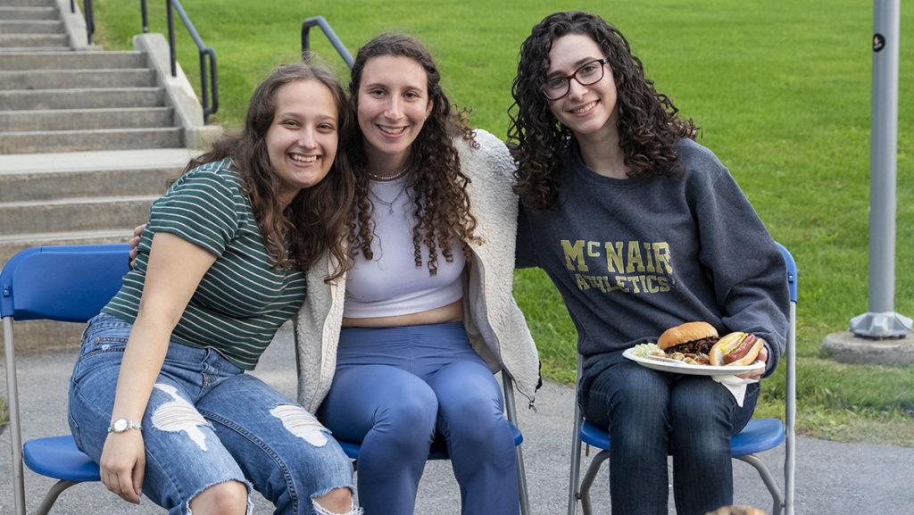 From left, juniors Felissa Gaber, Gabby Krain-Sasson and Rachel Gellman enjoy a Kosher barbecue and s’mores next to a campfire at a camp-themed Shabbat on Sept. 16 outside of Muller Chapel held by Hillel at Ithaca College.