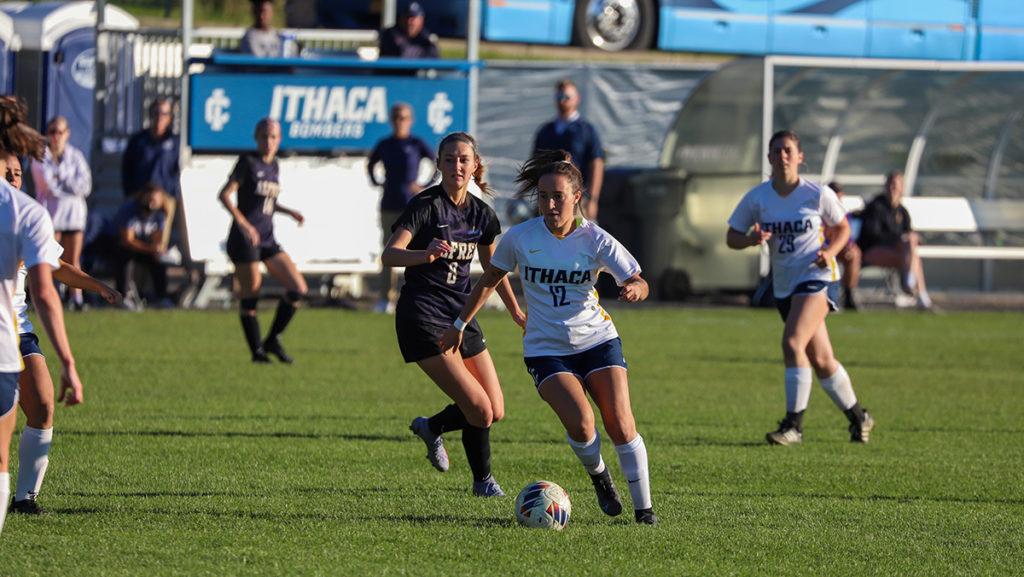 Graduate student midfielder Megan Buttinger dribbles the ball past Saxon sophomore midfielder Nyah Solly as junior midfielder trails the play during the Bombers 2–0 win over the Saxons.