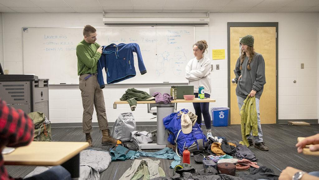 From left, senior Ben Vajdos, junior Juliann Vadney and sophomore Eleanor Wester hold a workshop for the Ithaca College Outing Club about what things to pack for a hiking trip Oct. 4.