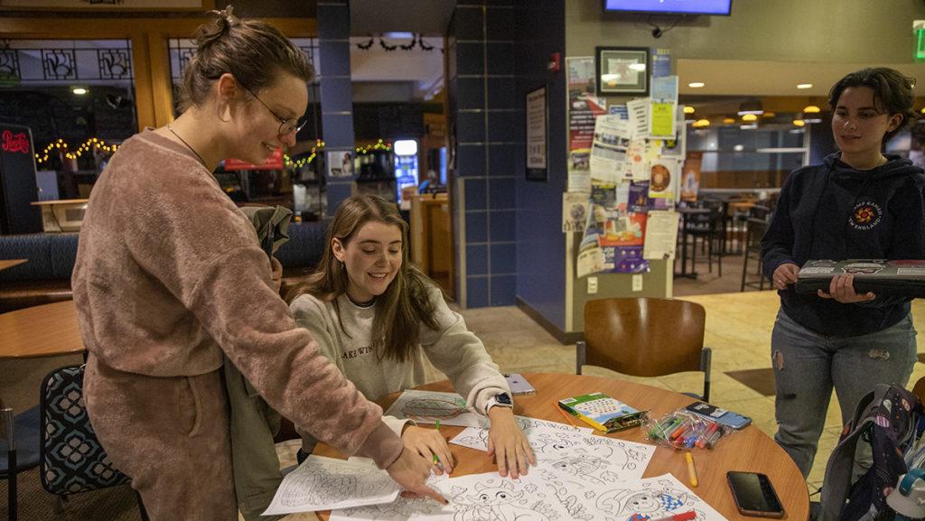From left, sophomores Zoe Williams, Hannah Goodrich and senior Shosh Cohen look at coloring pages during Theatre Lab in IC Square, a series of events intended for the campus community.
