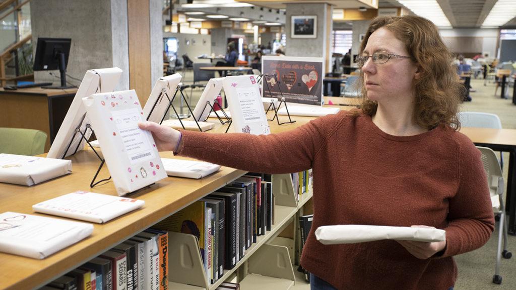 Sarah Shank, interlibrary loan borrowing coordinator at the Ithaca College Library, sets up a display for the Blind Date with a Book program. The program invites students to find new books and films.