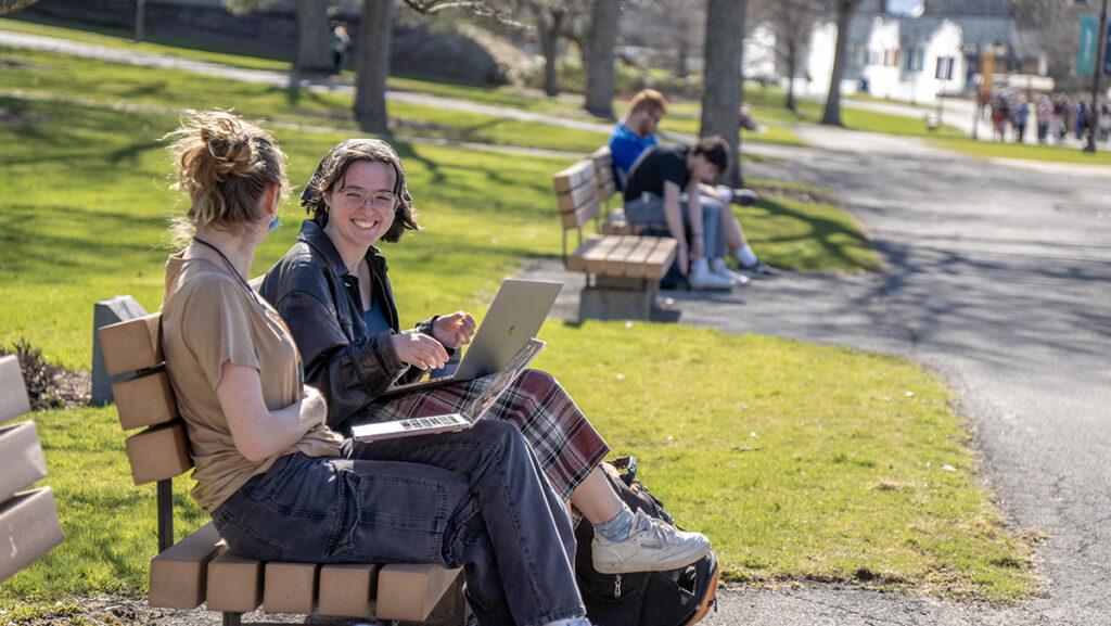From left, sophomores Johanna Tackitt and Claire Chesne spend time on a bench outside. More students are taking advantage of the outdoors and warm weather.
