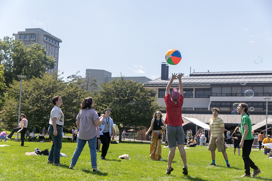 First-year students play a game of keep-it-up with a blown up beach ball during the fall orientations Pride Fest that was planned outside to accommodate more students. Others mingle and listen to music at the event in front of the Campus Center. 