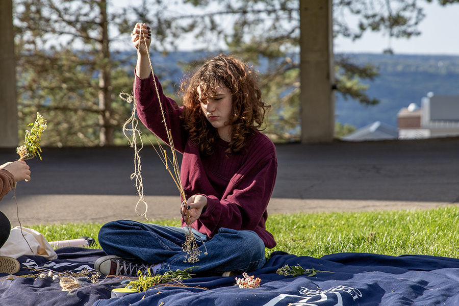 First-year student Eva Leon ties together a bouquet of dried flowers in the Ithaca College Terrace Quad at a bouquet making and DIY bookmark event hosted by Carly Dudek, Ithaca College Residence Director. 
