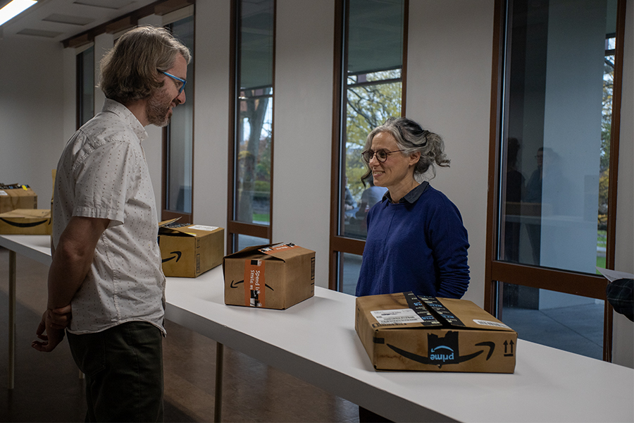 From left to right: Paul Wilson (art faculty at IC) and Joan Linder. Linder shows Wilson her art, realistic Amazon package creations meant to symbolize the waste habits of Americans. 