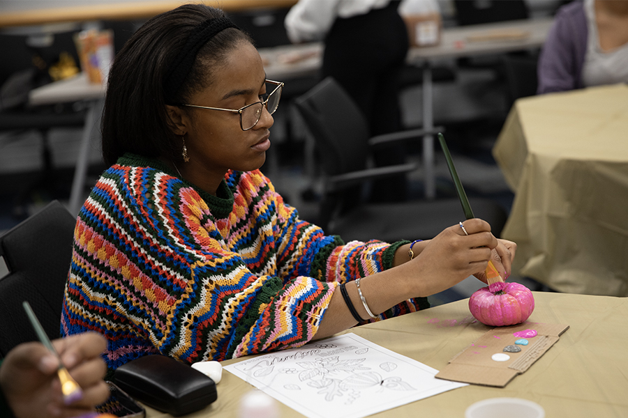 Junior Arjaye Johnson painting a pink mini pumpkin at the Pumpkin Paint and Sip hosted by Black Artists United on Oct. 21.