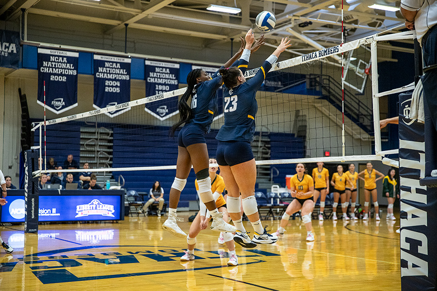 From left, junior middle blocker Anaya Prince and junior outside hitter Faith Sabatier leap for the ball in the Bombers 3–1 win on Senior Day.