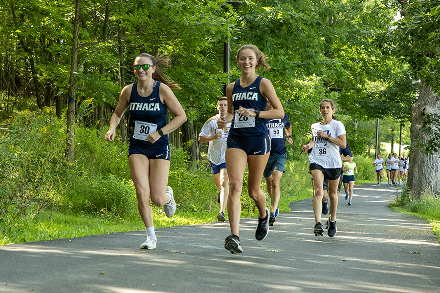 From left, junior runner Jillian Shea and sophomore runner Kayleigh Milligan run with each other during the Bombers first competition of the 2023 season.