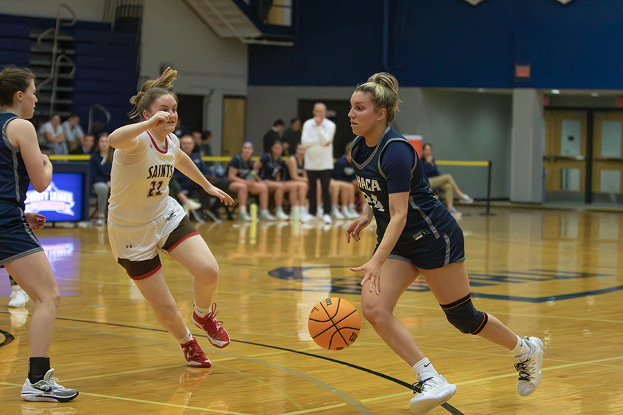 From left, Saints sophomore guard Jackie Malley slides right to try and intercept driving Bombers first-year guard Tori Drevna in the Bombers 60–51 victory Feb. 9.