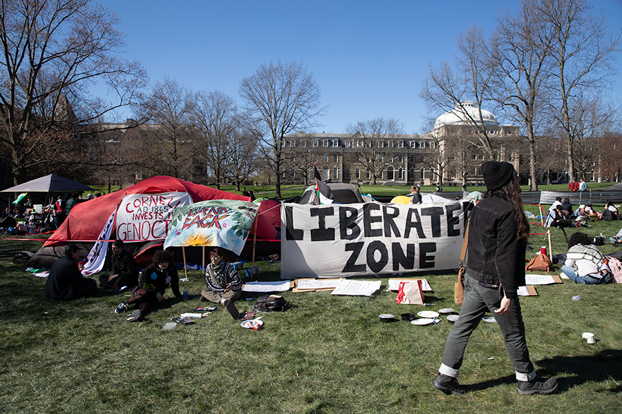 A student walks past the Liberated Zone encampment on Friday April 26. The encampment was created by the Pro-Palestine group Coalition for Mutual Liberation and it is intended to stay in place until Cornell agrees to their eight demands.