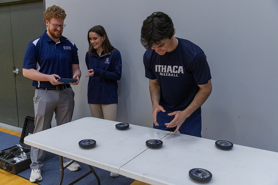 From left, graduate students Elie Kuhne and Kiley Mabus observe junior outfielder Collin Feeney as he participates in the FITLIGHT reaction time training. During the training, reaction time improved enough to react to the average Division I fastball.