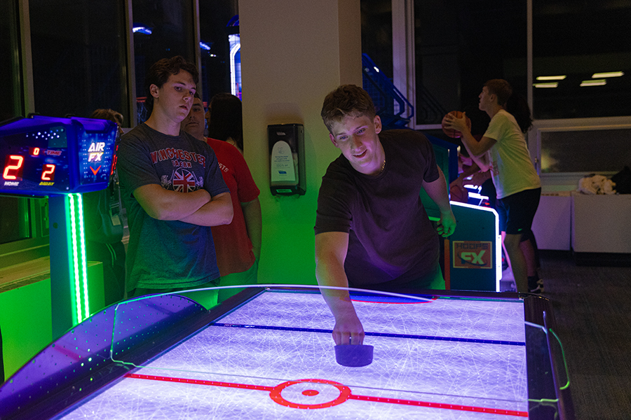 From left, first-year students Shea O’Reilly, Alexander MacKenzie and Dietrich Caler play a late-night game of air hockey together at the Res Life Neighborhood Event: Arcade and Game Night on Aug. 22 in the  Towers Marketplace.