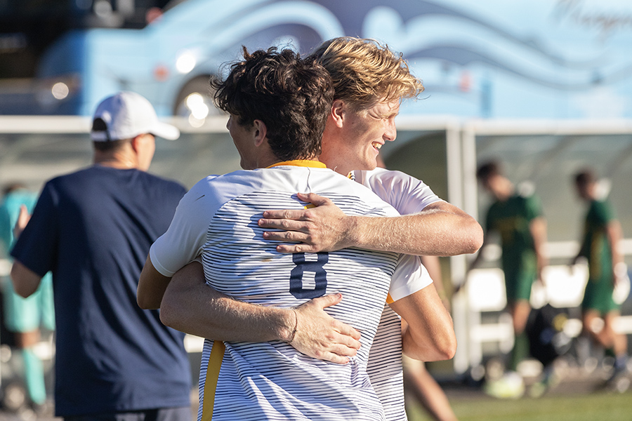 Junior forward Andrew Kusek and junior defender Riley Donelan hug each other in the Bombers' 3–1 victory over the SUNY Brockport Golden Eagles. After the win, the Bombers record goes to 3-1 for the season.