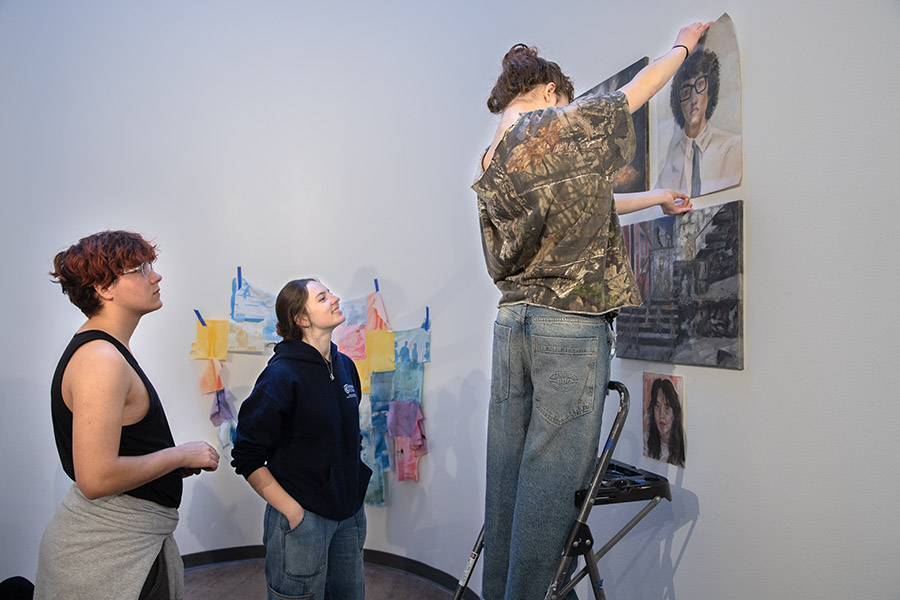 From left, seniors Alex Neuhedel, Isabella Sloan and Noami Rosenthal set up their artwork in the Rotunda Gallery for Prelude 13 which will open with a reception at 5:30 p.m. on Nov. 14. 