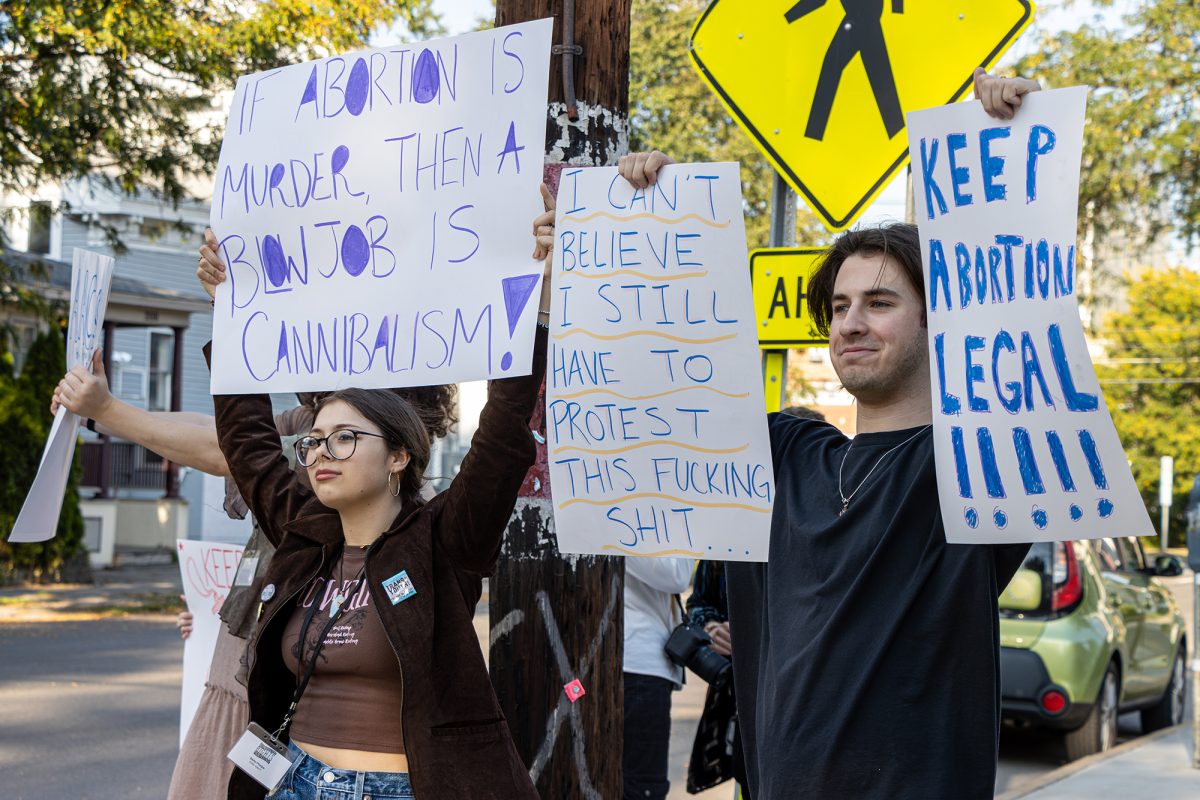 From left, sophomores Bella Phelps and Sam Rock protest held signs on the street corner in favor of the right to an abortion as the sound of passing car horns filled the street in support.