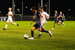 Bombers' junior midfielder Cameron Wooten dribbles past Red Dragons' first-year defender Jake Hutter on Sept. 17.