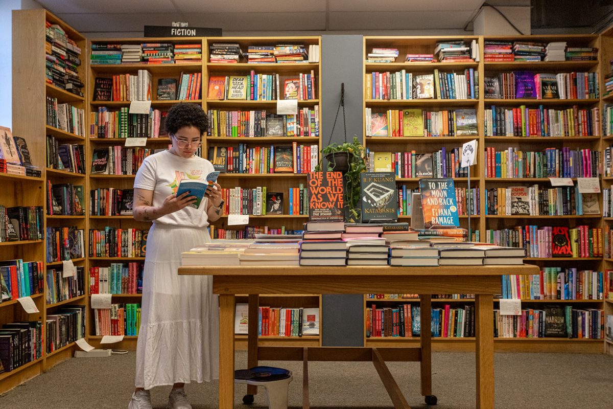 Gabriela Medina, Buffalo Street Books employee, peruses the bookstore's diverse fiction collection that aims to reflect the interests of the community while also introducing new perspectives. 