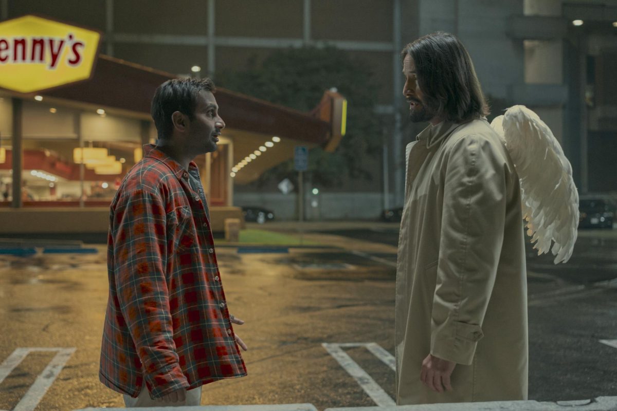 From left, Aziz Ansari and Keanu Reeves as Arj and angel Gabriel in "Good Fortune" stand facing each other in a parking lot.