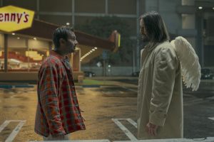 From left, Aziz Ansari and Keanu Reeves as Arj and angel Gabriel in "Good Fortune" stand facing each other in a parking lot.