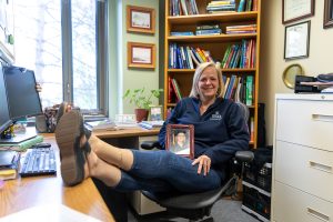 Shannon Scott, associate professor in the Ithaca College Department of Occupational Therapy, sits at her desk in her office, holding a photo of herself from the graduation ceremony for her doctorate degree in 2015.